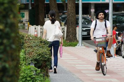 Rear view of women walking on bicycle