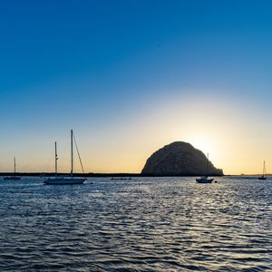 Sailboats in sea against clear sky