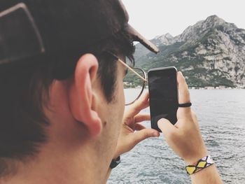 Midsection of man using mobile phone against mountain
