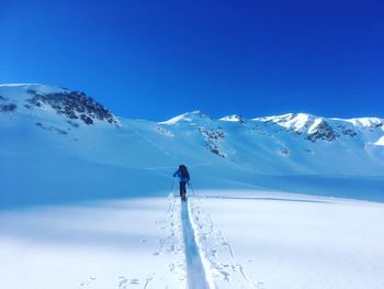 Man skiing on snowcapped mountain against blue sky