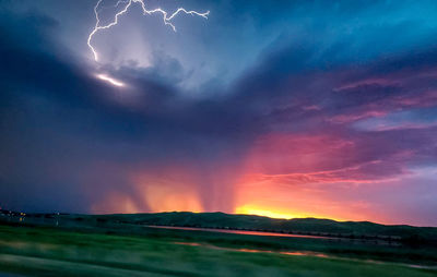 Scenic view of storm clouds over landscape during sunset