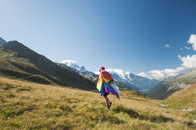 Man with lgbtiq community flag in mountains