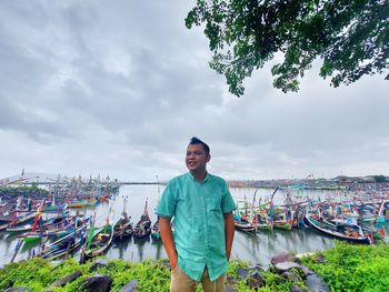 Man standing by boat against sky