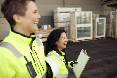 Happy multiracial female colleagues walking in distribution warehouse