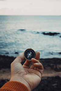 Cropped hand holding navigational compass at beach