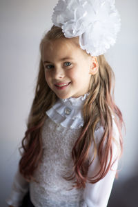 Portrait of smiling girl standing against white wall