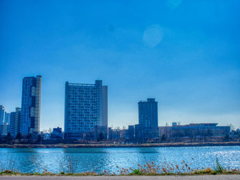 River by buildings against sky in city