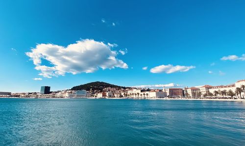 Scenic view of sea by buildings against blue sky