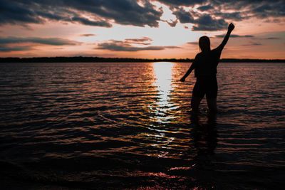 Silhouette man standing on beach against sky during sunset