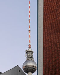 Low angle view of communications tower against sky in city