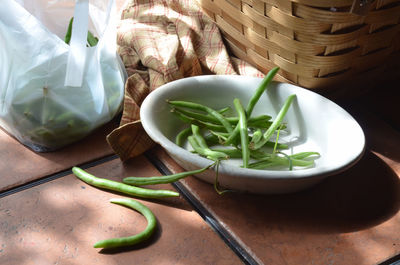 Green beans, white dish with prepared green beans ready for cooking, baske on outdoor table