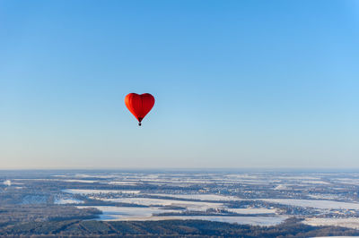 Aerial view of red heart shape hot air balloon against blue sky