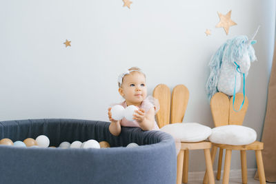 One-year-old girl playing with balls near the dry pool in the children's room