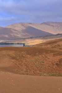1154 sumu barun jaran lake in badain jaran desert-dark water reflecting cloudy sky and dunes. china.
