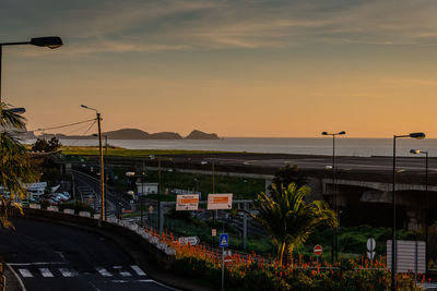 Street by sea against sky during sunset