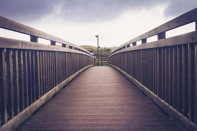 Footbridge over footpath against sky