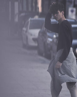 Young man walking on sidewalk in city