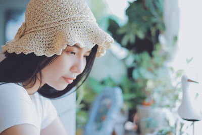 Thoughtful young woman wearing hat while looking away at home