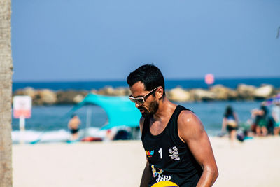 Man wearing sunglasses at beach against sky