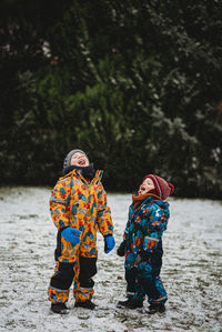 Rear view of boys standing on snow during winter