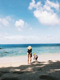 Rear view of women on beach against sky