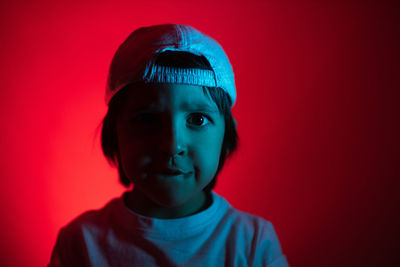 Cyberpunk boy in a white t-shirt and cap stands against the wall and thinks