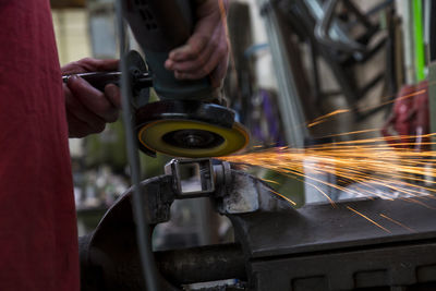 Midsection of worker using circular saw at workshop