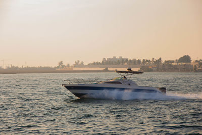 Speedboat on sea against clear sky during sunset