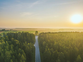 Scenic view of road amidst green land against sky during sunset