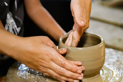 Midsection of people working on pottery wheel