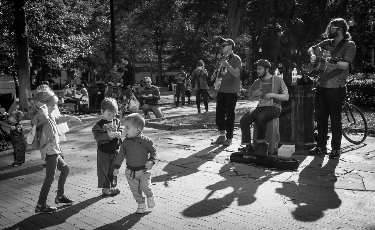 men, street, lifestyles, large group of people, person, walking, leisure activity, full length, sunlight, city life, shadow, casual clothing, tree, city, togetherness, road, day, sidewalk, outdoors