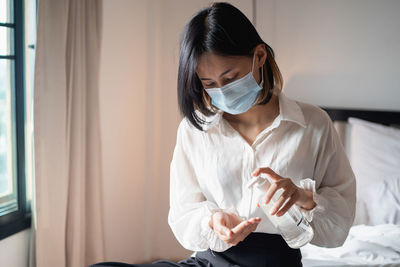 Young woman using hand sanitizer