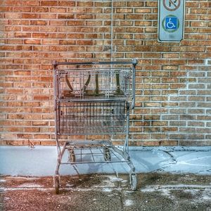 Abandoned shopping cart against brick wall