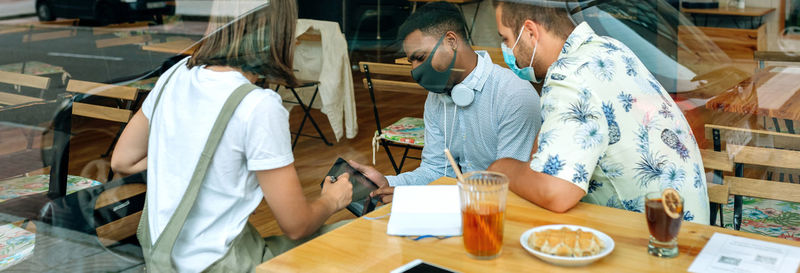 Cheerful friends wearing mask sitting at restaurant