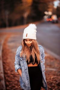 Portrait of smiling young woman in hat standing outdoors