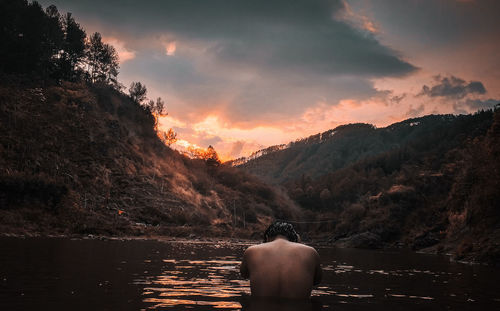 Rear view of man looking at mountain against sky