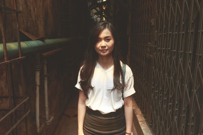 Portrait of young woman standing in alley