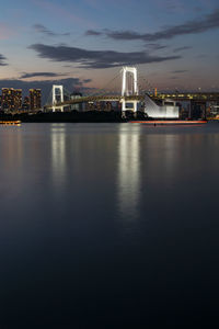 View of bridge over tokyo bay with buildings in background during sunset in odaiba.