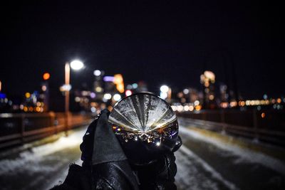 Close-up of hand holding illuminated city against sky at night
