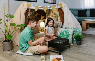 Cute sibling barbecuing food at home