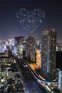 Illuminated buildings in city against sky at night