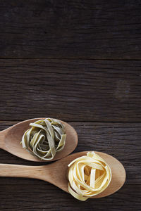 Close-up of tagliatelle pasta in wooden spoons on table