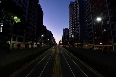 Road passing through illuminated city at night