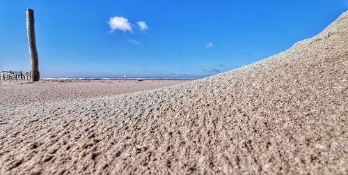Surface level of sand dune on beach against blue sky