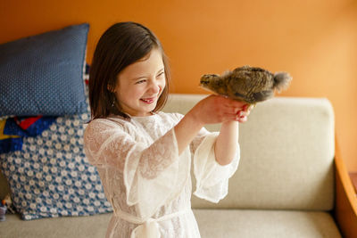 A joyful child holds a baby bird up close to her face to study it