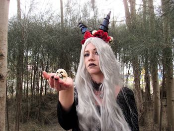 Portrait of woman holding camera in forest