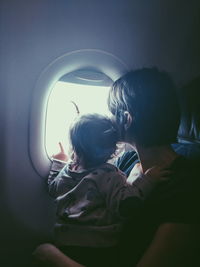 Mother and daughter looking through window in airplane