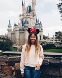 Portrait of happy woman standing against building