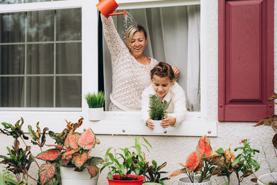 Portrait of young woman and girl standing by potted plant