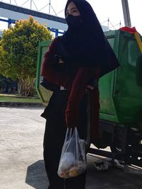 Woman standing by car in city